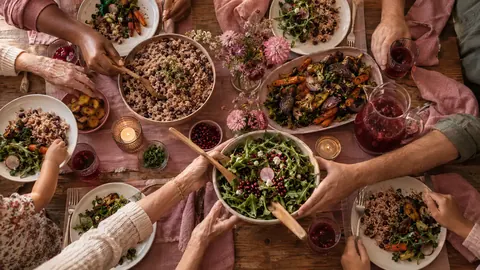 Hands passing dishes around a family table
